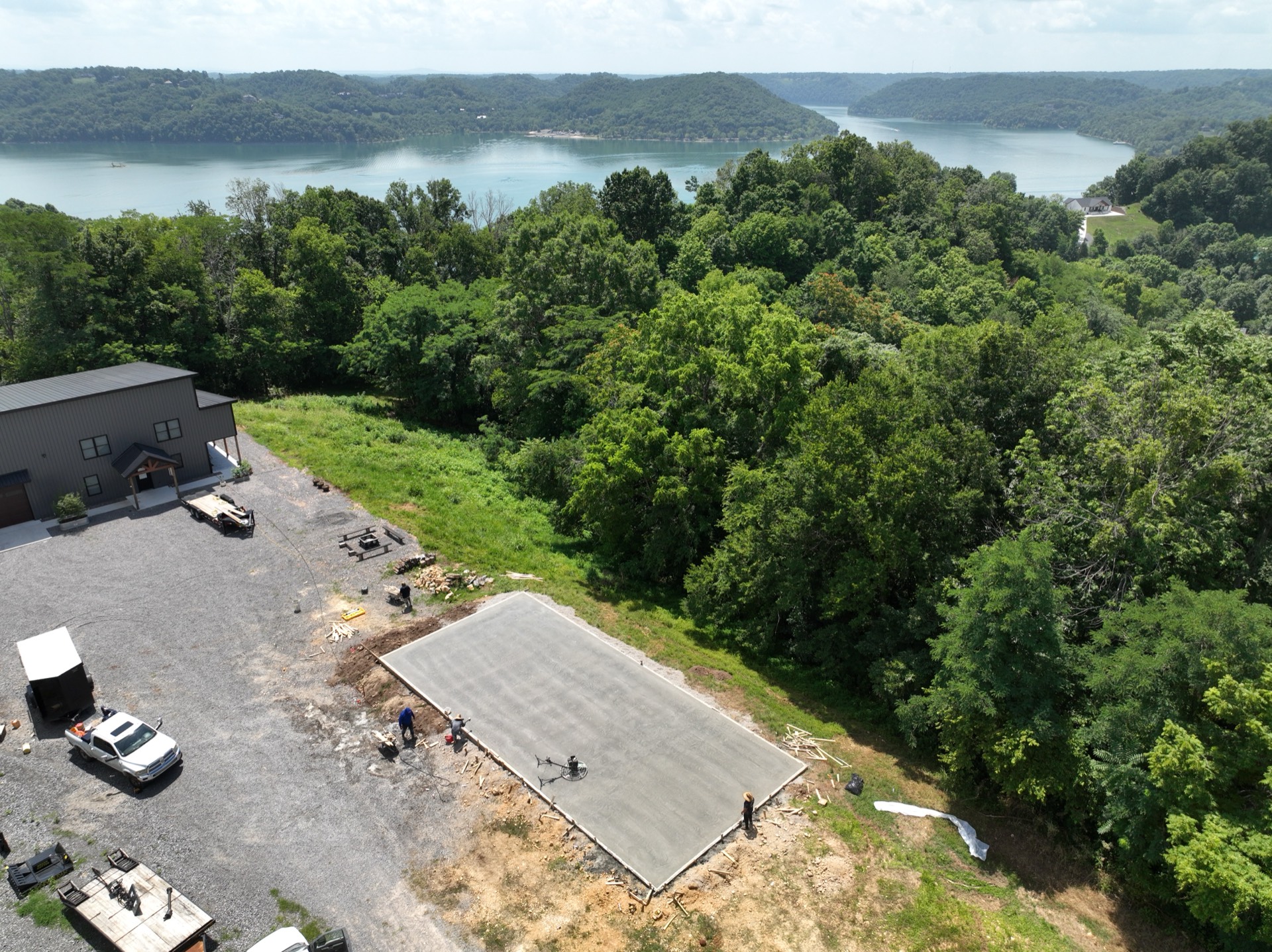 Aerial view of a fresh concrete building pad poured on a bluff lot overlooking a lake