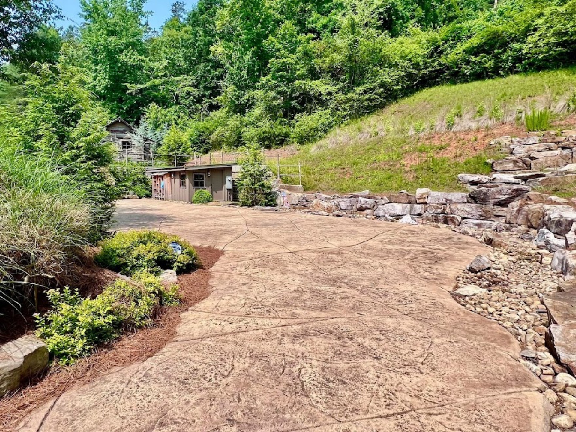 Large stamped concrete patio with a seamless-stone finish and natural stone retaining walls